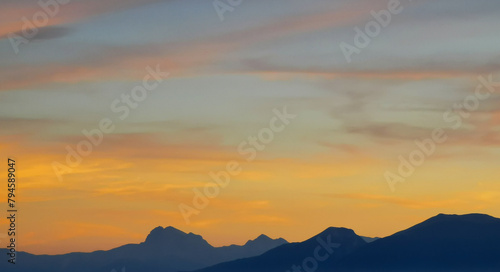 Luminoso tramonto arancio e ocra sopra le montagne italiane