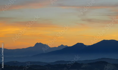 Luminoso tramonto arancio e ocra sopra le montagne italiane © GjGj