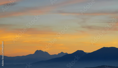 Luminoso tramonto arancio e ocra sopra le montagne italiane