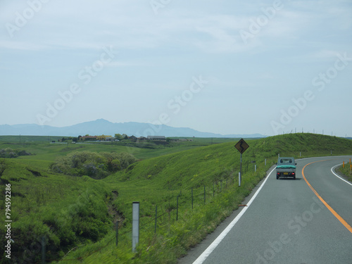 Car Driving by the road through the green valley on sunny day, travelling on Kyushu concept with distant Mount Aso famous volcano  photo