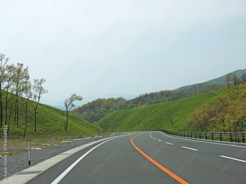 Travelling on Kyushu, driving on lonely road with lush green grass on roadsides on sunny day