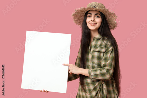 Beautiful young happy woman with blank poster on pink background. Festa Junina (June Festival) celebration