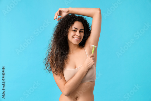 Beautiful young happy woman with razor on blue background. Depilation concept © Pixel-Shot