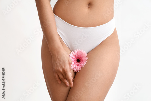 Beautiful young woman in panties with gerbera flower on white background, closeup