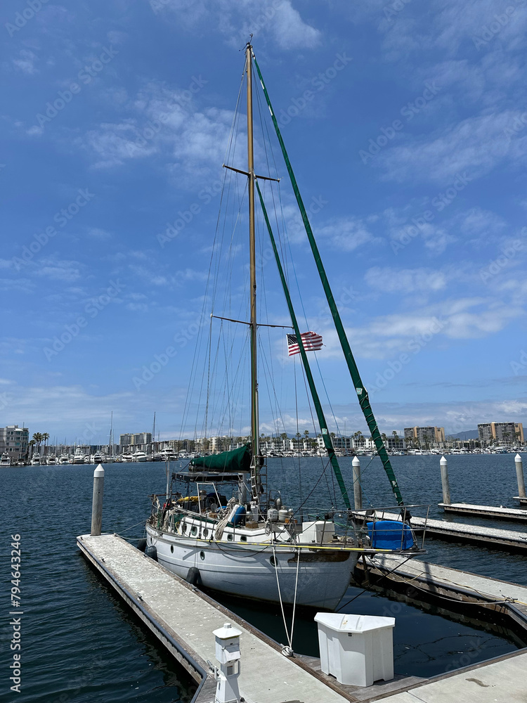 Cutter sailboat docked at a small marina by itself flying small american flag