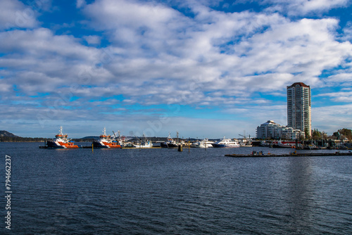 Beautiful Nanaimo city skyline. Multi-storey buildings and a marina for boats and yachts in the bay against the background of a blue cloudy sky