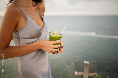 Cropped image woman hold in hand  green vegetable smoothie on the beach