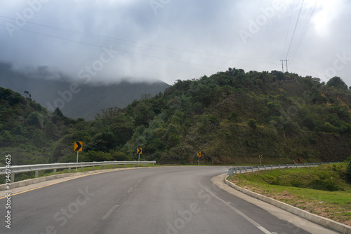 Two-lane highway with traffic signs and mountains in the background. Colombia