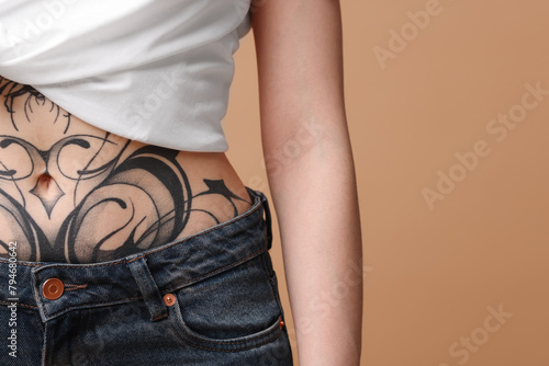 Woman with cool tattoos on beige background, closeup. Space for text