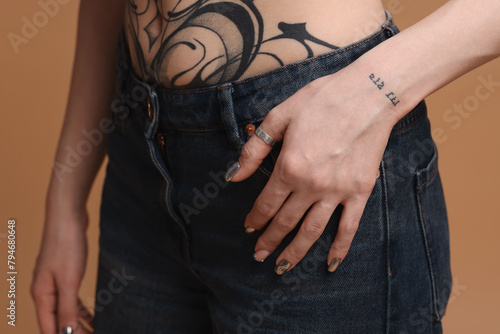 Woman with cool tattoos on beige background, closeup