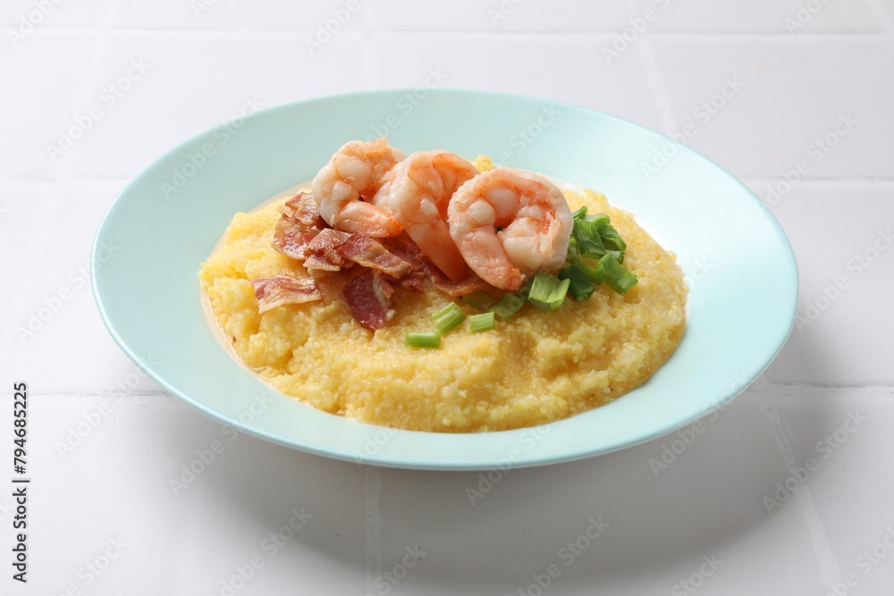 Plate with fresh tasty shrimps, bacon, grits and green onion on white tiled table Plate with fresh tasty shrimps, bacon, grits and green onion on white tiled table