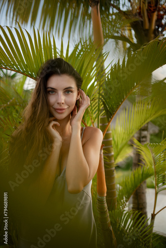 Beauty. Woman model with long straight hair and palm leaves. Caucasian girl with beautiful  face at tropical nature