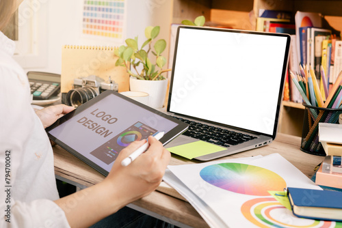Designer at work on a table, selecting color shades for creative graphic design with laptop and tablet