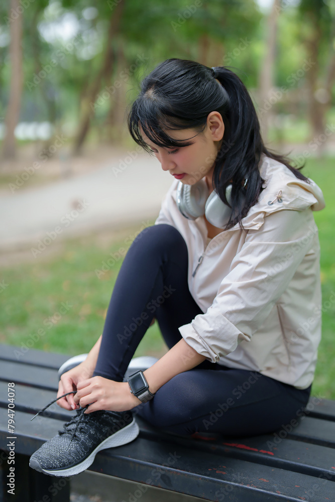 Young asian sporty women sitting on bench and tying shoelaces running to getting ready for jogging training while workout and exercise for healthy wellness lifestyle in the morning at outdoor park Young asian sporty women sitting on bench and tying shoelaces running to getting ready for jogging training while workout and exercise for healthy wellness lifestyle in the morning at outdoor park