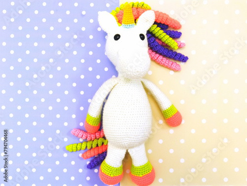 A crochet toy of a white unicorn, handmade pony on colorful background. Amigurumi