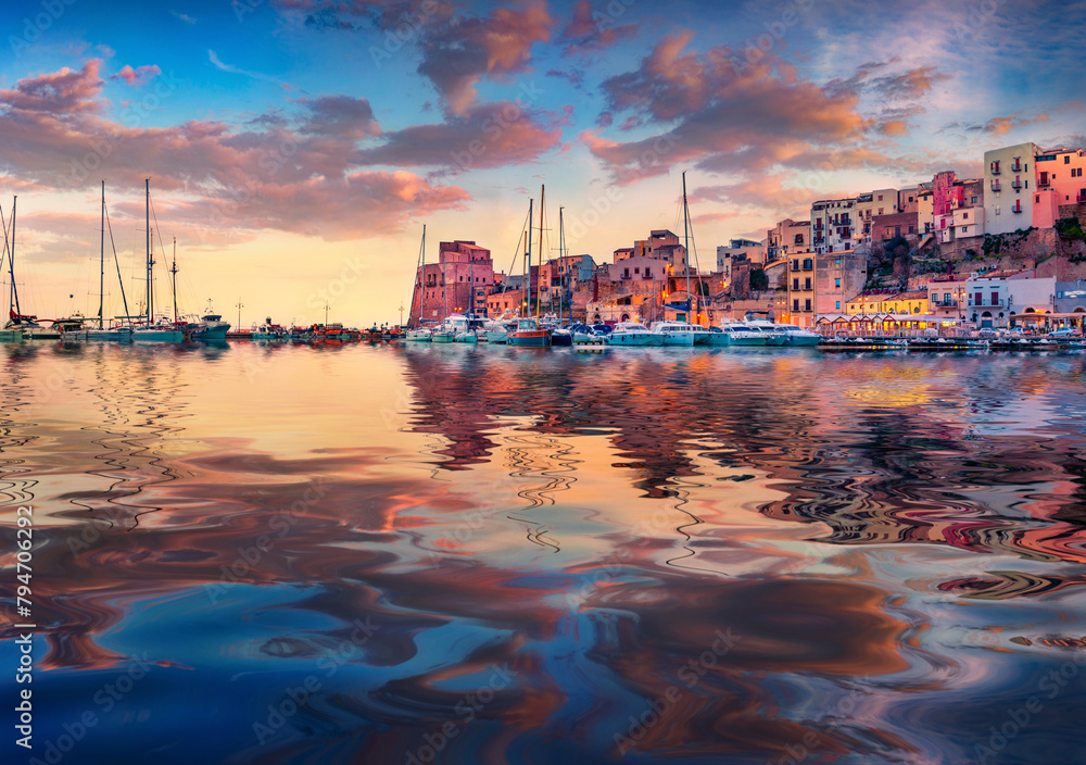 Naklejka premium Colorful building of Castellammare del Golfo port reflected in the calm waters of Mediterranean sea. Picturesque sunrise in Sicily, Trapani Province, Europe. Traveling concept background.