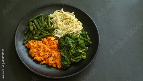 Urap, Indonesia traditional food served on plate. Salad dish consist of steamed vegetables such as sprouts, long beans, and mustard with seasoned and spiced grated coconut. photo