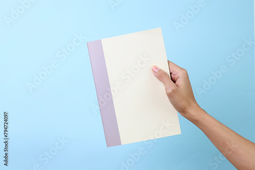 Woman holding yellow book with blank cover for mockup isolated on blue background