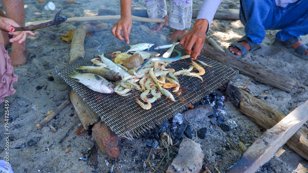 Obraz premium The Activities Of People Grilling Fish And Shrimp On The Beach