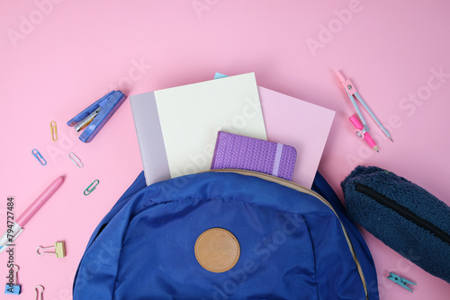 Backpack with school supplies on pink background. Back to school concept. 