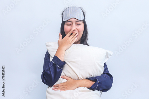 Young Woman in Pajamas Yawning While Holding Pillow Isolated on Gray Background
