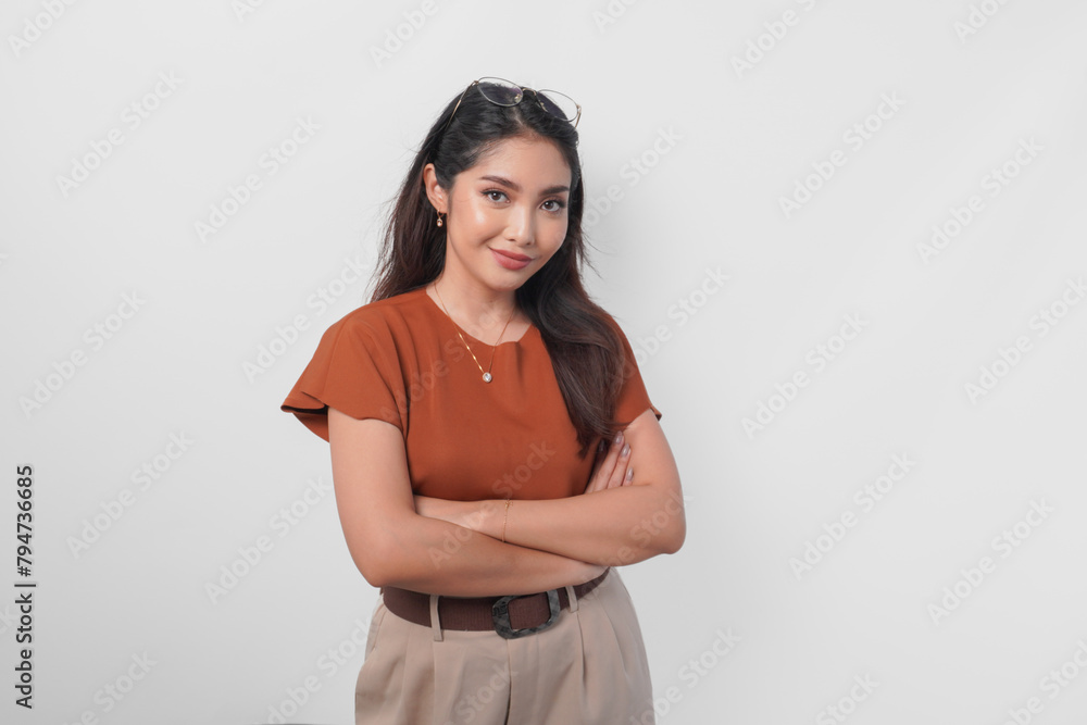 Obraz premium Confident Asian woman standing with arms folded and looking at the camera isolated over white background.
