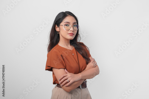 Young Asian woman standing with arms folded and looking at the camera with confident expression isolated over white background.