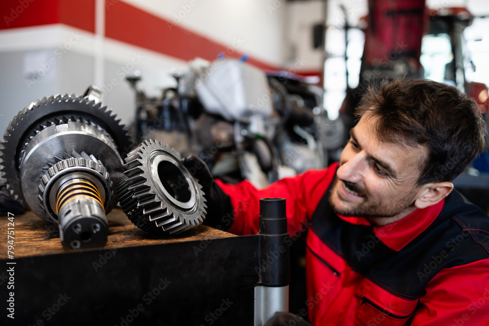 Experienced mechanic or serviceman holding gears parts inside workshop. Experienced mechanic or serviceman holding gears parts inside workshop.