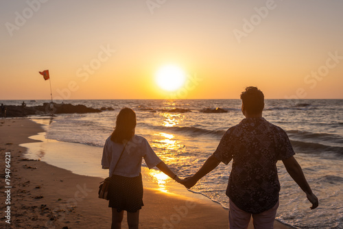 Young Indian Couple enjoying the spectacular sunset at Anjuna Beach in Goa
