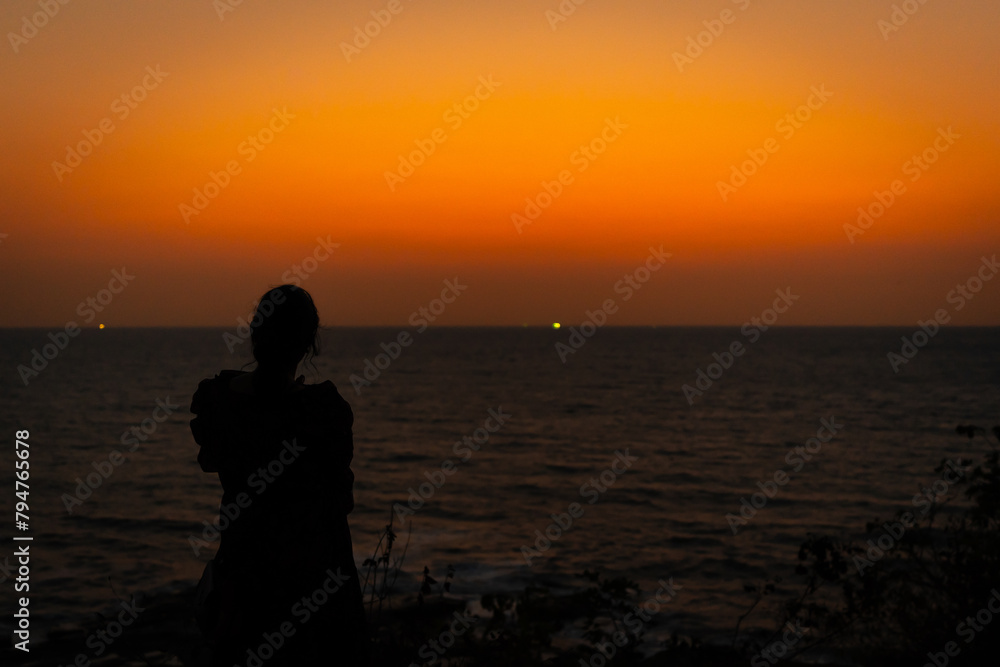 silhouette of woman standing and feeling free at sunset
