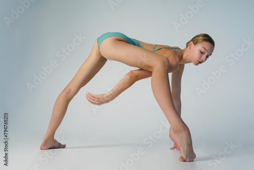 young ballerina in a bodysuit stands in a lunge leaning forward with one foot on the toe