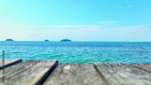 The tranquil turquoise sea  framed by a wooden bridge  leads the eye to a distant island under a vibrant blue sky  crafting a mesmerizing  idyllic setting. Koh chang  Trat Province  Thailand.  