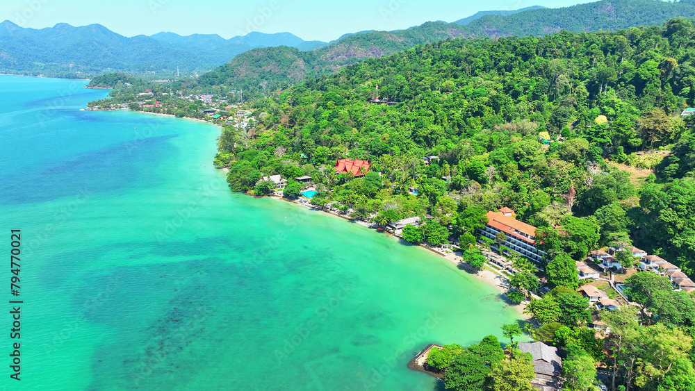 Pristine beaches meet turquoise waters, flanked by luxurious resorts, framed by lush mountains, under a clear blue sky. Landmarks and nature concept. Ko Chang island, Thailand. 
