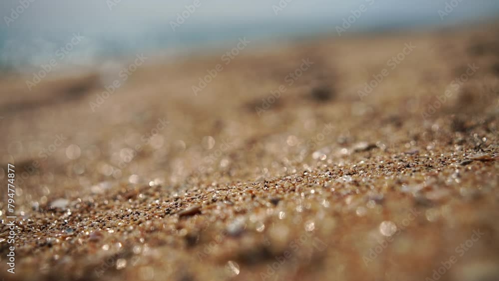 Sand flows in slow motion against the bokeh background of the beach and sea. Sand flows in slow motion against the bokeh background of the beach and sea.