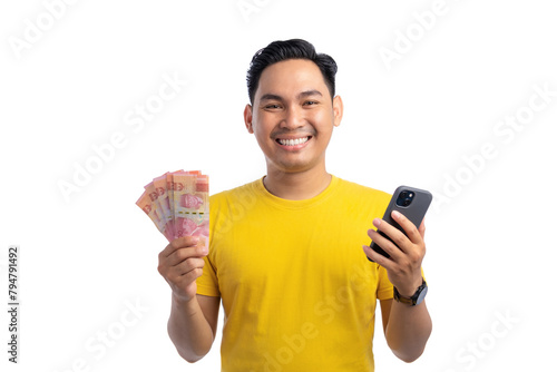 Happy young Asian man holding smartphone and money, looking at the camera and smiling isolated on white background