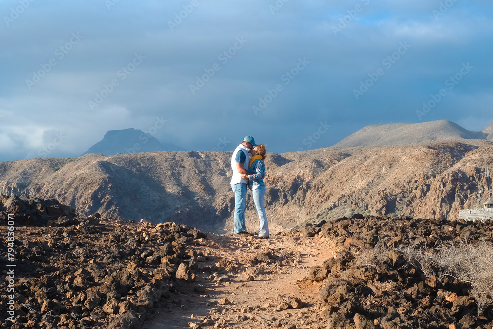 Active couple enjoy hiking outdoors leisure activity together in volcanic scenery destination. Travel people lifestyle. Adventure and hike active lifestyle outside. Mountain and sky backgorund