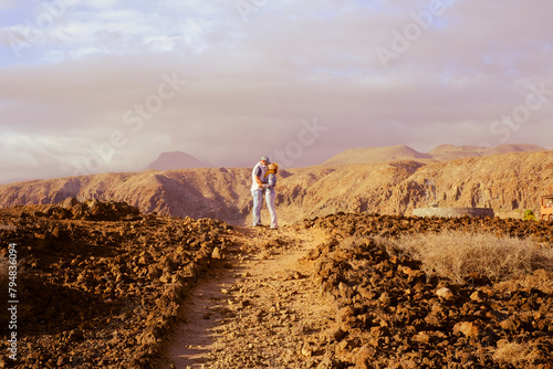 Active couple enjoy hiking outdoors leisure activity together in volcanic scenery destination. Travel people lifestyle. Adventure and hike active lifestyle outside. Mountain and sky backgorund photo