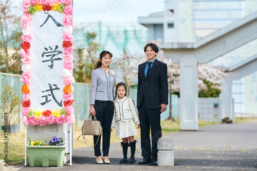 小学校の前で入学式の記念写真を撮る日本の親子