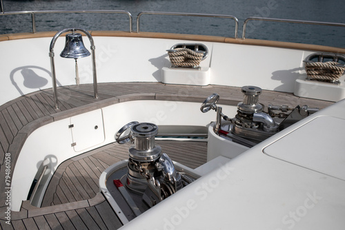 Anchor winches and ship bell mounted at the prow of a luxury motor yacht