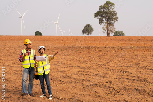 Female and male engineers discuss installing wind turbines, clean energy that reduces carbon emissions.