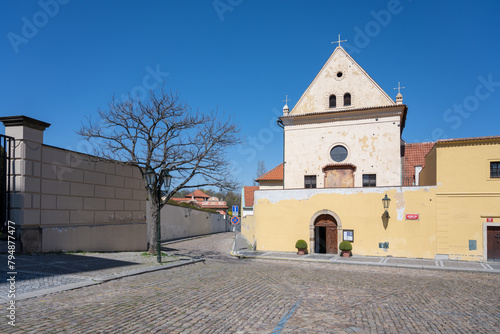 The picturesque Church of the Virgin Mary Angelic stands under a clear blue sky in Hradcany, Prague, Czechia, with its distinctive facade and entrance visible. photo