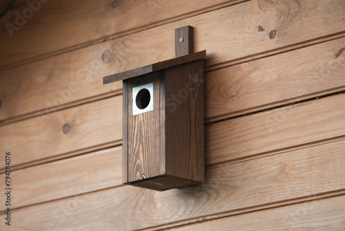 Wooden birdhouse on a wooden wall, close-up.
