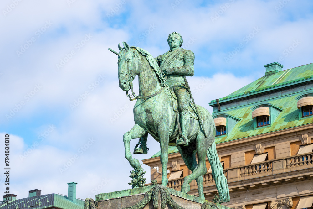 The statue of Gustav II Adolf is captured here standing proudly in Stockholm, Sweden, with clear skies and surrounded by the city architecture.