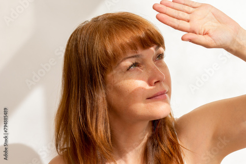 Portrait of caucasian middle aged woman close her face by hand hiding from sunlight
