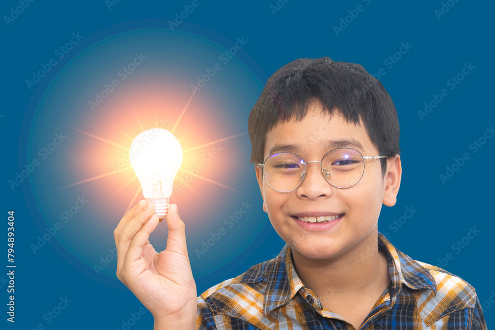 Preteen boy holding glowing light bulb lamp in hand, looking at camera with smile. creativity, thinking out of the box, idea and science concept Preteen boy holding glowing light bulb lamp in hand, looking at camera with smile. creativity, thinking out of the box, idea and science concept