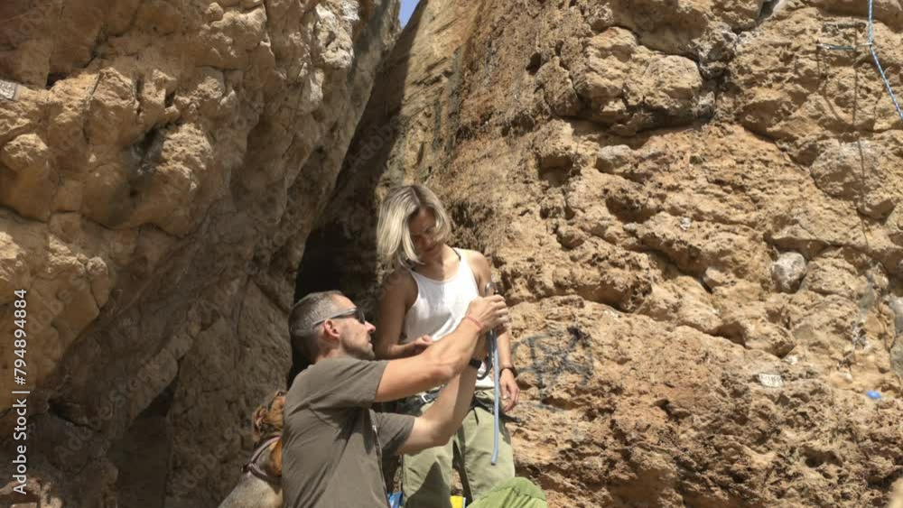 A man and a woman are standing in a rocky area, with the man holding a rope A man and a woman are standing in a rocky area, with the man holding a rope