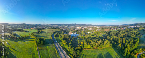 Aerial view capturing the evening glow of summer sunrise bathing the city of Liberec and the iconic Jested Mountain Ridge in warm light, with the serene landscape. Czechia