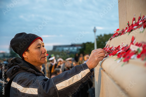 Obraz na płótnie Man placing red poppies on the wall at the Court of Honour. Unrecognizable people in uniform in the background. Anzac Day commemoration. Auckland Domain. w salonie