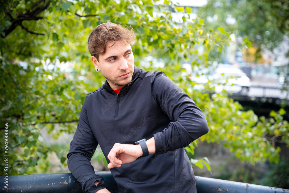 Sportsman looking at smartwatch with blank screen outdoors. - obrazy, fototapety, plakaty 