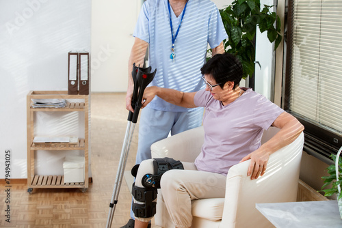 A male nurse helps to put a bondage, medical splint, knee brace on the leg of an elderly female patient who communicates with the attending physician at the clinic or hospital. photo